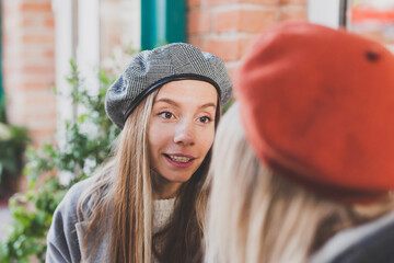 Portrait young female best friends talking to each other discussing interesting themes during free time hipster girls joking and having fun together enjoying recreation with coffee to go on urban