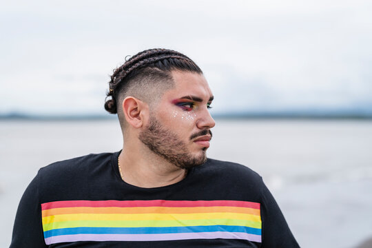 Retrato Horizontal De Un Hombre Gay Maquillado Y Peinado Con Trenzas Y Barba Mirando A Un Lado Muy Serio Y Pensativo Al Aire Libre