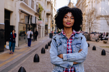young black haitian woman looks at the camera with crossed arms, urban look and very confident. copy space