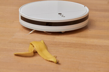 Robotic vacuum cleaner on laminate wood floor smart cleaning technology. banana