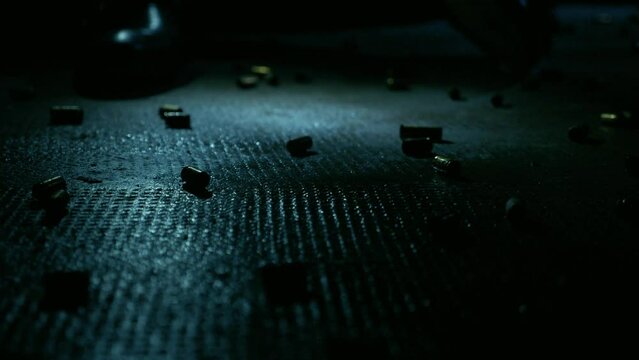 Man in Black Suit Sits on a Floor Full of Gun Shell Casings with Flicking Lights
