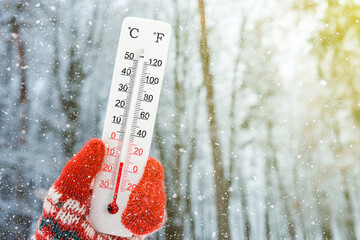 White celsius and fahrenheit scale thermometer in hand. Ambient temperature minus 13 degrees celsius