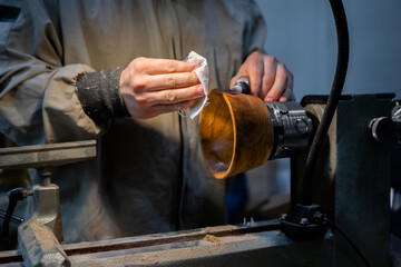 Professional carpenter oiling finished wooden bowl on wood lathe. Handmade, woodwork, carpentry and craftsmanship concept