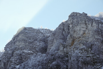 Amazing light falling on top of the steep cliff with frozen, silver trees during winter - 549839408