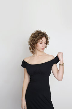 Serie of studio photos of young female model in long elastic black classic and versatile off the shoulder dress 
