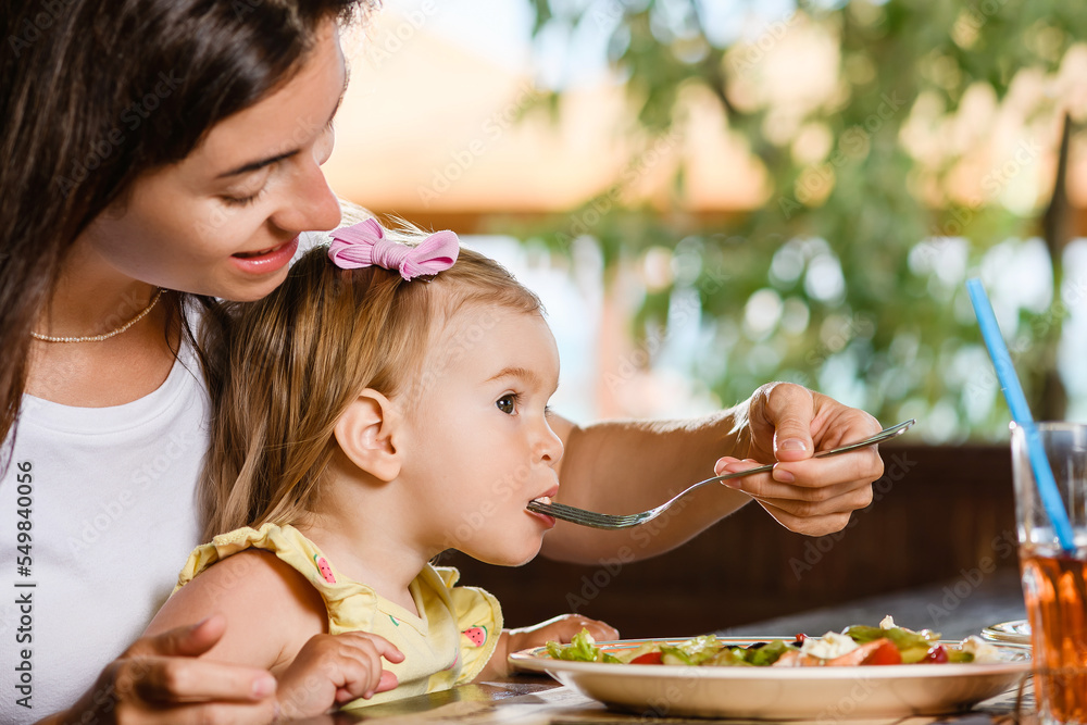 Wall mural woman mom feed toddler girl with salad