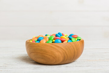 Multicolored candies in a bowl on a colored background. birthday and holiday concept. Top view with...