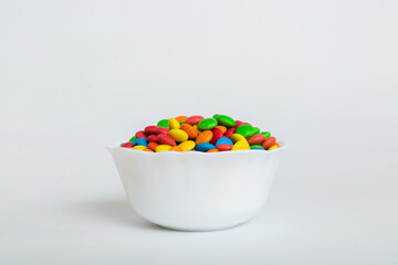 Multicolored candies in a bowl on a colored background. birthday and holiday concept. Top view with...