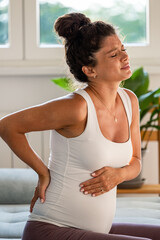 Fototapeta na wymiar Pregnant woman having back pain while sitting on sofa