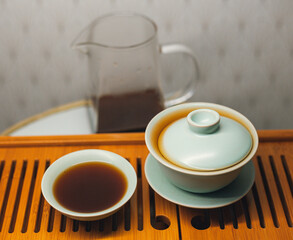 Cups, chaban selective focus. Gongfu cha tea ceremony. Zhu-yao Chinese ceramics on a bamboo tea board. Brewing Chinese tea in ceramic dishes gaiwan, chahai, cups during the tea ceremony close-up.
