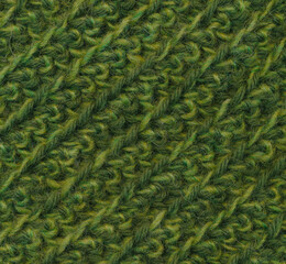 Fabric crocheted with green wool yarn, close-up background.