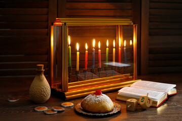 Jewish holiday Hanukkah with menorah (traditional Candelabra), donuts and wooden dreidels (spinning top), chocolate coins.  Inscription on the menorah 