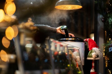 Fototapeta premium Human hand pouring mulled wine into a boiler on a German Christmas market at a stand in Hanover