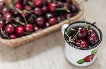 Straw basket with cherry and enameled metal mug with washed cherry.