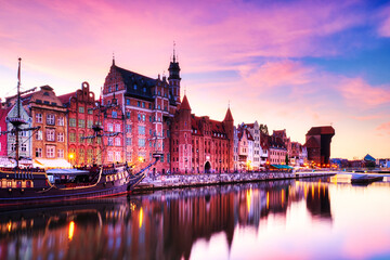 Obraz premium Illuminated Gdansk Old Town with Calm Motlawa River at Sunset, Poland