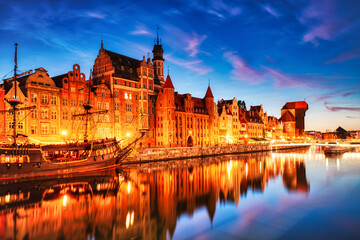 Obraz premium Illuminated Gdansk Old Town with Calm Motlawa River at Dusk, Poland