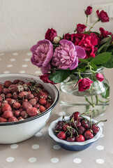 Strawberries, cherry in a ceramic plate and a bouquet of peonies.