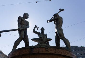 Three smiths statue sculpture on blue sunny day