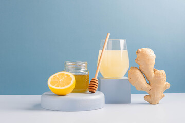 Antioxidant drink fresh ginger lemon honey glass trendy blue background, podium minimalism, balance