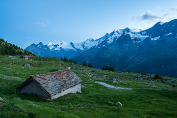 Fototapeta na wymiar Old alpine hut with stone roof during blue hour