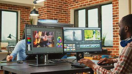 African american freelancer working on video filmmaking at agency workstation, creating professional content. Video editing designer using cinematography software to edit film or movie montage.