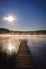 Obraz na płótnie Canvas Beautiful summer morning landscape. Wooden pier on the lake shore in the misty morning scenery. Photo taken in Michala Gora, Poland.