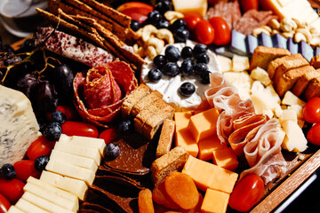 Cheese platter, cheese board meat and board. Vegetables and fruits with cheese and chocolate, prosciutto and salami with bread. Big board of snacks for the party.