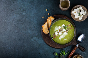 Broccoli cream soup in a bowl with toasted bread and cheese