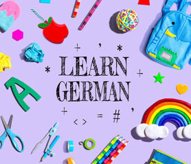 Learn German theme with school supplies on a purple background - flat lay