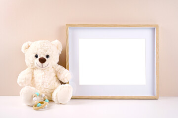 Artwork picture frame product mockup. Baby shower 1st birthday Christening gender neutral party. Styled setting with white teddy bear against a beige and white background. Negative copy space.
