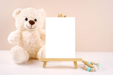 Table number easel with 5x7 card product mockup. Baby shower 1st birthday Christening gender neutral. Styled setting with white teddy bear against a beige and white background. Negative copy space.