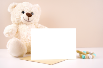 5x7 horizontal greeting card party invitation product mockup. Baby shower birthday christening gender neutral. Styled with white teddy bear against a beige and white background. Negative copy space.