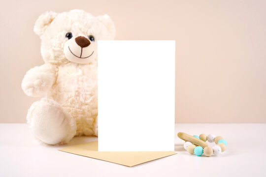 5x7 vertical greeting card party invitation product mockup. Baby shower birthday christening gender neutral. Styled with white teddy bear against a beige and white background. Negative copy space. - Powered by Adobe