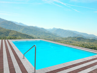 Outdoor swimming pool at luxury resort with beautiful view of mountains on sunny day