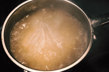 boiling water in silver pan. a bag of cooked rice in a pan
