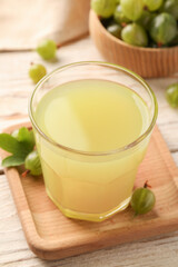Tasty gooseberry juice and fresh berries on wooden table, closeup