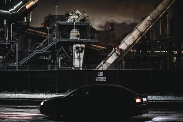 Fotobehang Car driving near a factory at night © Patryk Rydzewski/Wirestock Creators