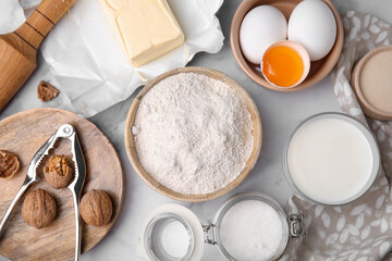Bowl of flour and other ingredients in white table, flat lay