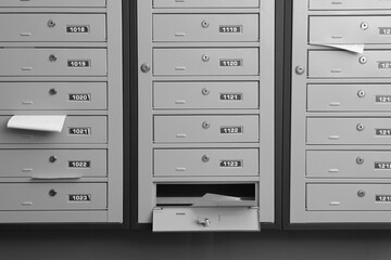 Grey metal mailboxes with receipts and envelopes indoors