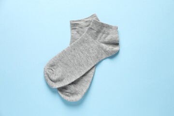 Pair of grey socks on light blue background, flat lay