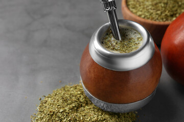 Calabash with mate tea and bombilla on light grey table, closeup. Space for text