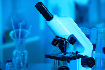 Closeup view of modern microscope with glass slide in laboratory, toned in blue. Space for text
