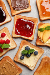 Tasty toasts with different spreads and fruits on light grey table, flat lay