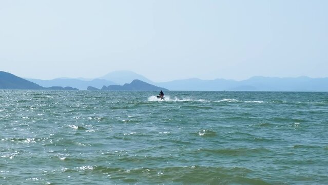 On a jet ski at sea. A man on blue waves rides a scooter.