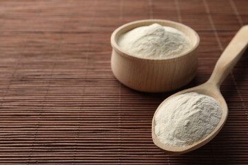 Bowl and spoon of agar-agar powder on bamboo mat, closeup. Space for text