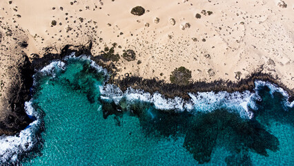 Aerial view of the rocky coastline of the Corralejo Natural Park in the north of Fuerteventura in the Canary Islands, Spain - Desertic barren landscape in the Atlantic Ocean
