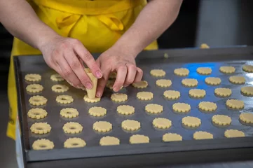 Wandcirkels aluminium Female hands making holes in biscuit dough © Nadja Knapp/Wirestock Creators