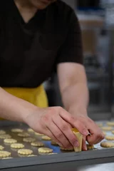 Keuken foto achterwand Female hands making holes in biscuit dough © Nadja Knapp/Wirestock Creators