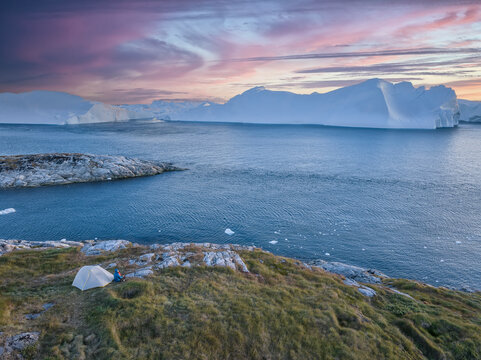 camping with a tent in fron of big icebergs