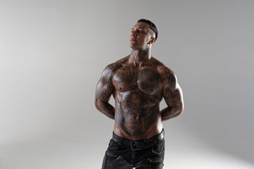 Handsome brutal man with tattoo holding belt and watching us. hot sportive guy in studio. bodybuilder. punisher